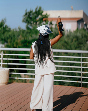 Graduate in cap and gown holds champagne bottle